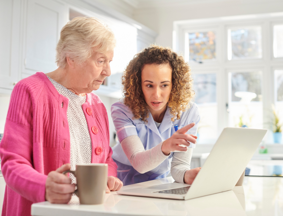 Caregiver assisting an elderly woman with computer use.