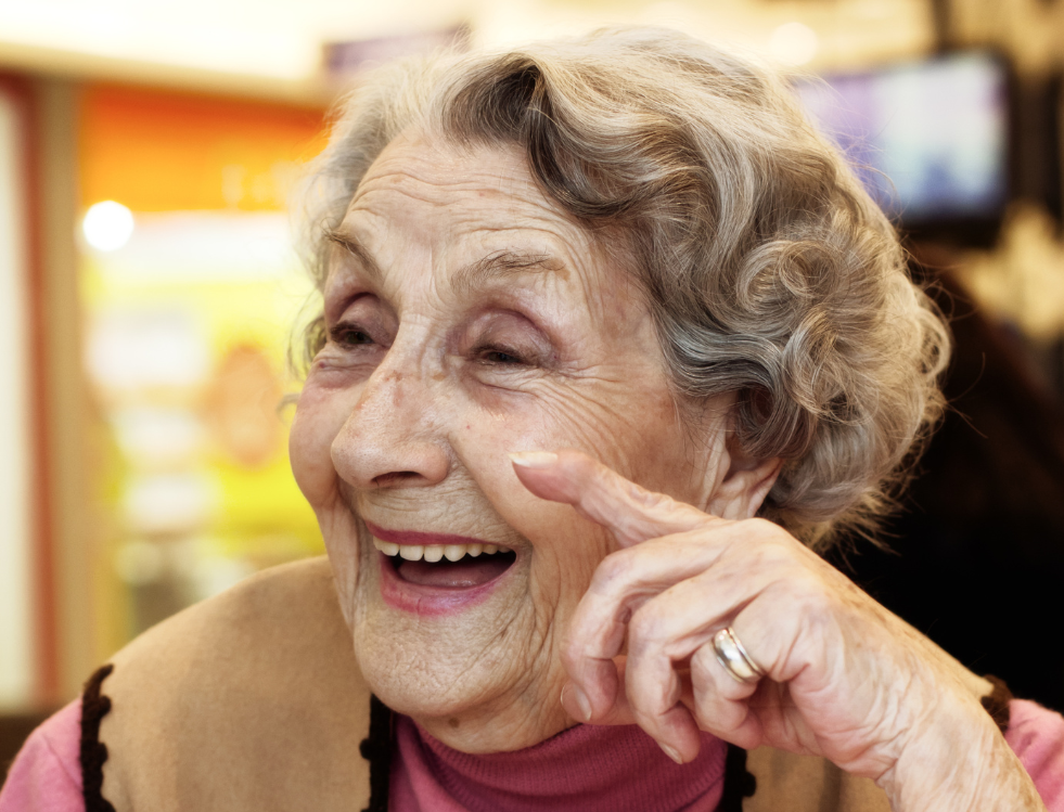 An elderly woman smiling and enjoying a joyful moment in a Jewish homecare setting.