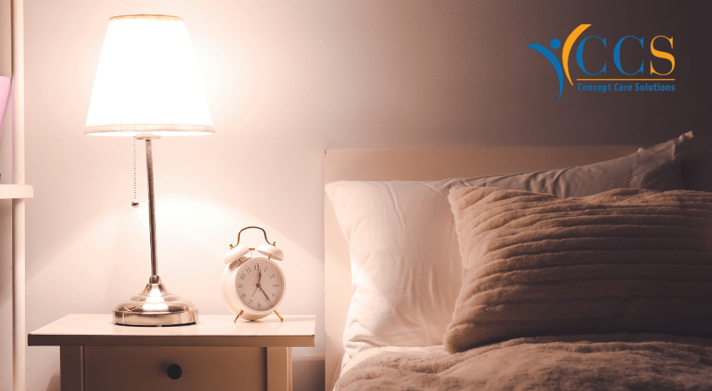 Cozy bedroom with a bedside table, lamp, and alarm clock, highlighting a peaceful environment for overnight care services.