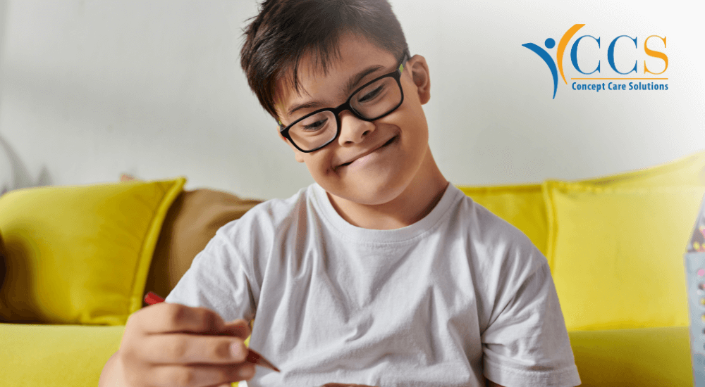 A child with Down syndrome smiling while drawing with colored pencils, representing the inclusive and supportive environment provided by Concept Care Community Services.