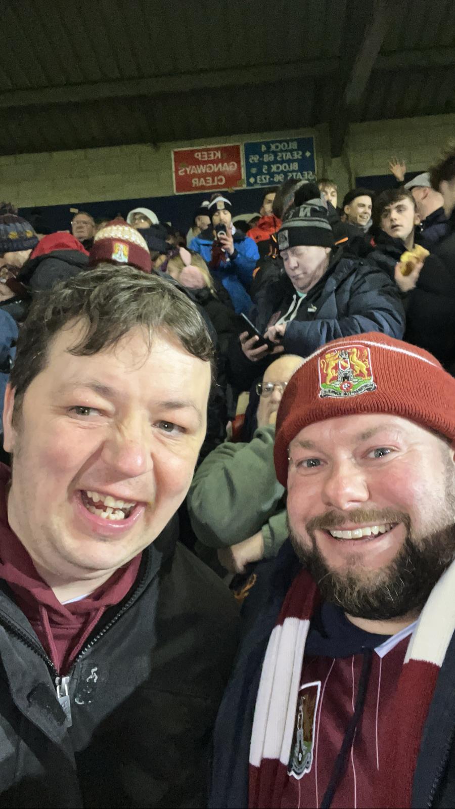 Carer and client enjoying a football match together, smiling in the stadium crowd.