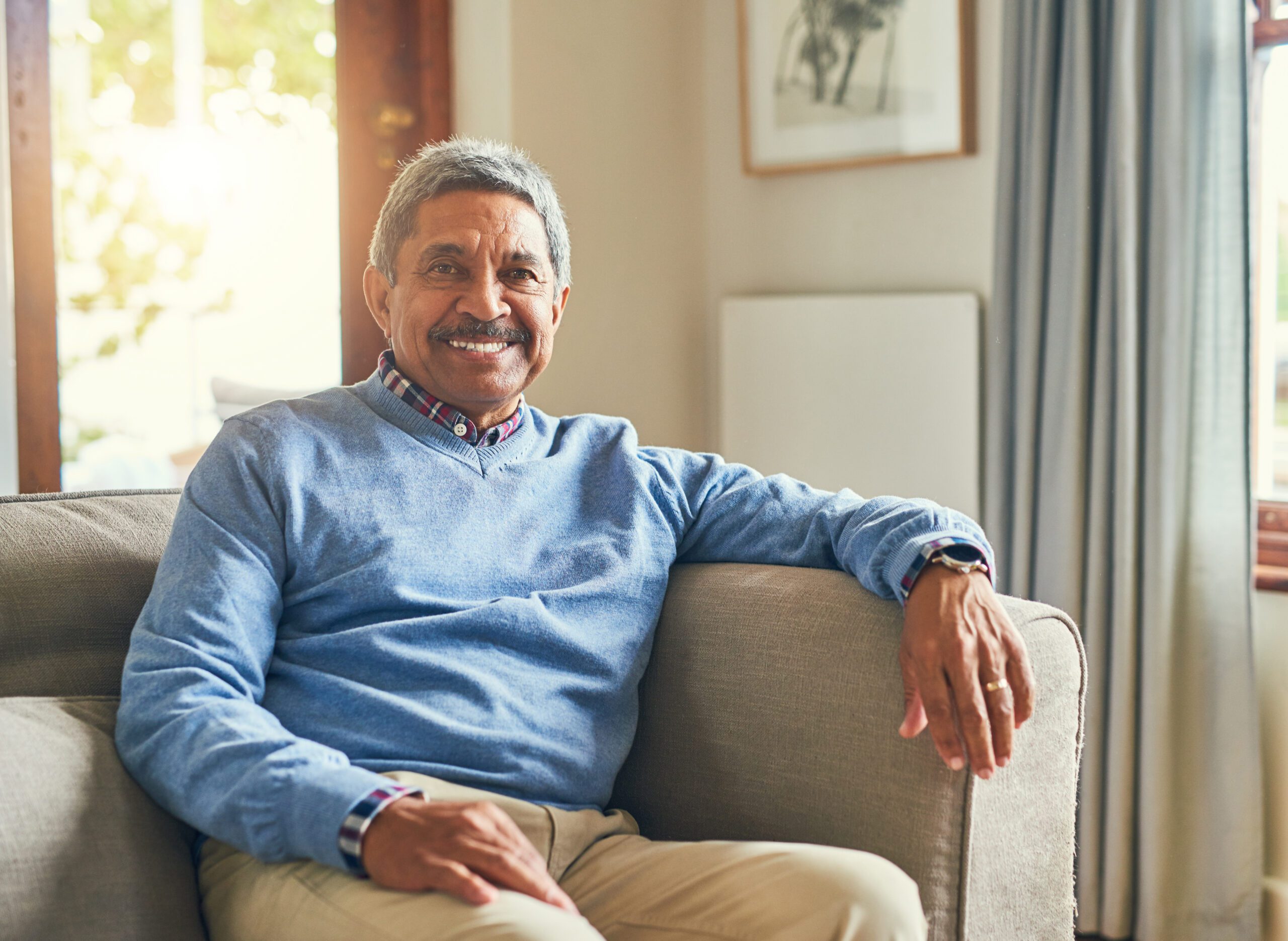Smiling elderly Indian man relaxing at home with peace of mind